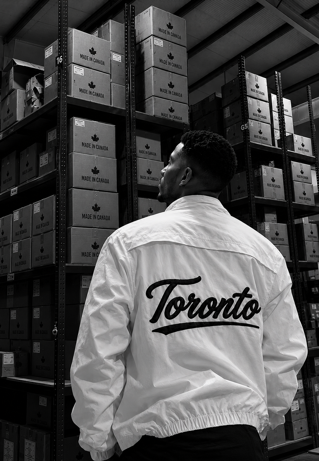 The back view of a man wearing a white jacket featuring "Toronto" printed across the shoulders.