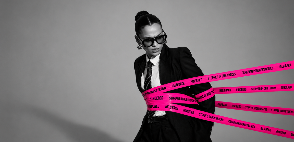 A woman wearing a blazer, tie, and sunglasses with her hands tied behind her back with pink tape that reads "Stopped in our tracks. Canadian progress denied".