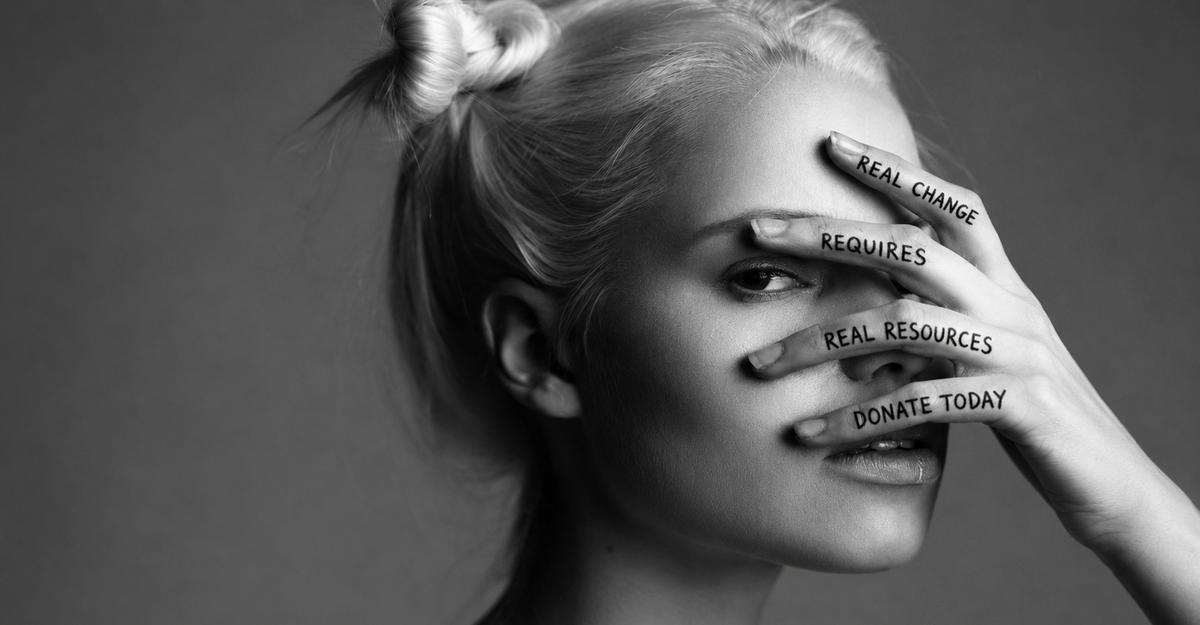 A portrait of a woman with her hand on her face, featuring the words "Real changes require real resources. Donate" written across her fingers.
