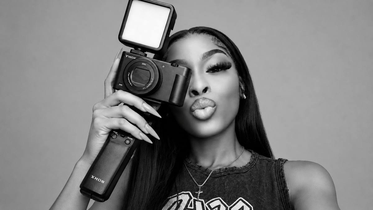 A woman pouting her lips while looking directly through the viewfinder of a camera.